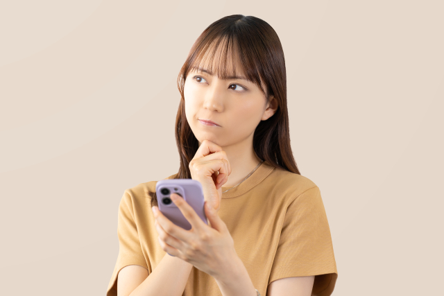 スマートフォンを持ち考え事をしている女性。